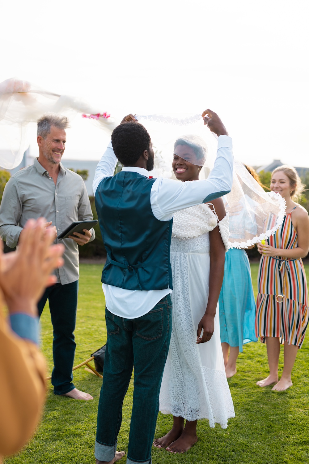 Happy african american couple holding veil and smiling during wedding. Wedding day, friendship, inclusivity and lifestyle concept.